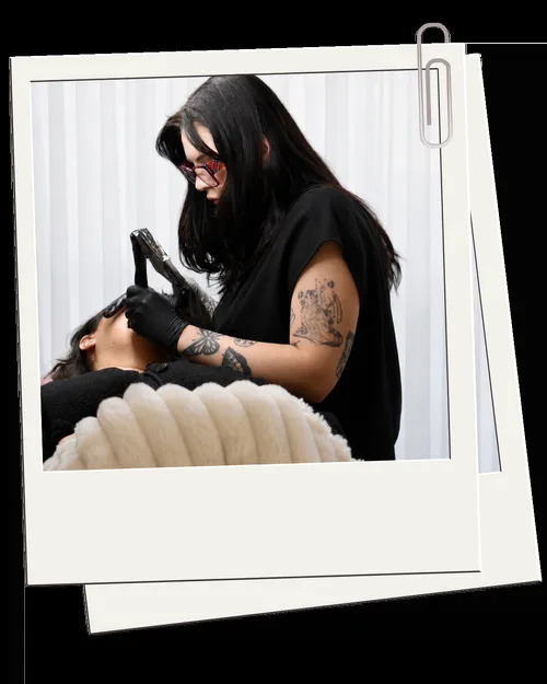 Kirra performing a cosmetic tattooing treatment on a reclined client — the work in action